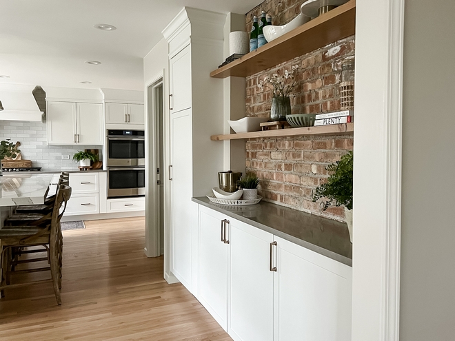 A wall with exposed brick and floating shelves brings warmth to this kitchen
