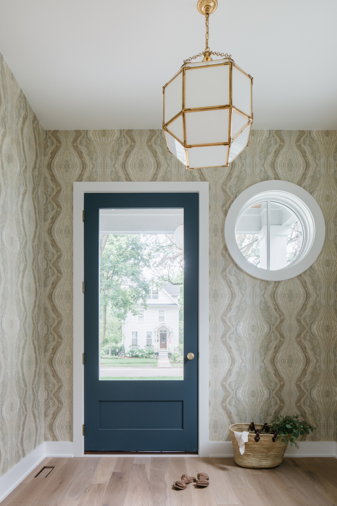 A blue door wallcoverings and a round window bring plenty of character to this charming foyer #foyer