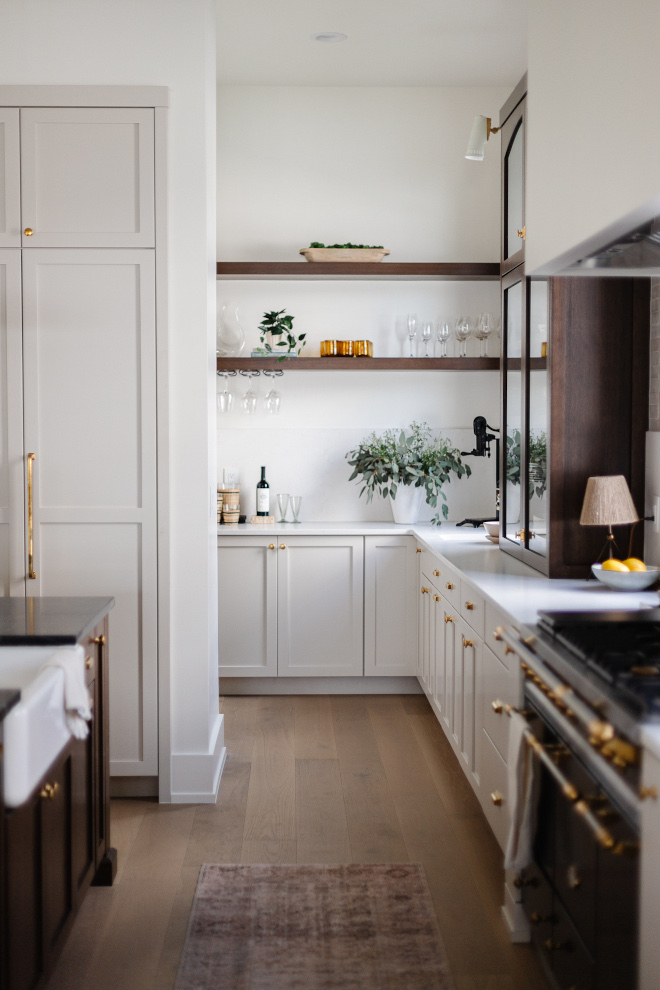 Kitchen flows into a l-shaped butlers pantry with window-height slab backsplash and custom floating shelves #kitchen