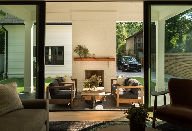 The family room sliding doors open to a covered patio with a painted brick fireplace with beam mantel This outdoor living area truly feels like an extension of the home #outdoorlivingarea