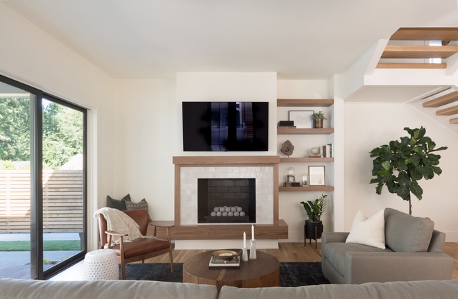 Living room features an asymmetrical fireplace with a Walnut bench on the left and Walnut floating shelves on the right Fireplace tile zellige tile surround is the perfect finishing touch #livingroom