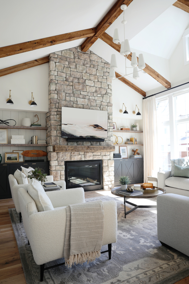 In the Great Room vaulted ceilings with custom beams are anchored by a floor-to-ceiling stone fireplace with custom cabinets #GreatRoom #vaultedceilings #beams #floortoceilingfireplace #stonefireplace #customcabinets