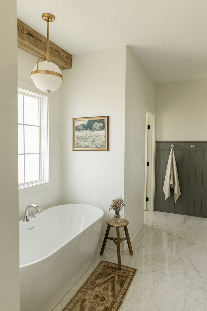 Designing a neutral bathroom is trickier than it seems and the designer did it perfectly here Wainscoting along with a reclaimed ceiling beam in the tub nook add the right amount of texture and patina in this classic bathroom