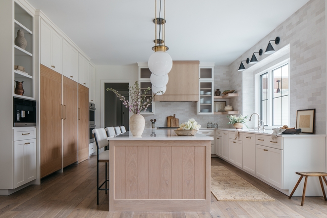 In the kitchen a combination of white cabinets and light White Oak along with neutral textured tiles and warm finishes create a welcoming and inviting sensation #kitchen #whitecabinets #lightWhiteOak #neutraltile #texturedtiles #finishes