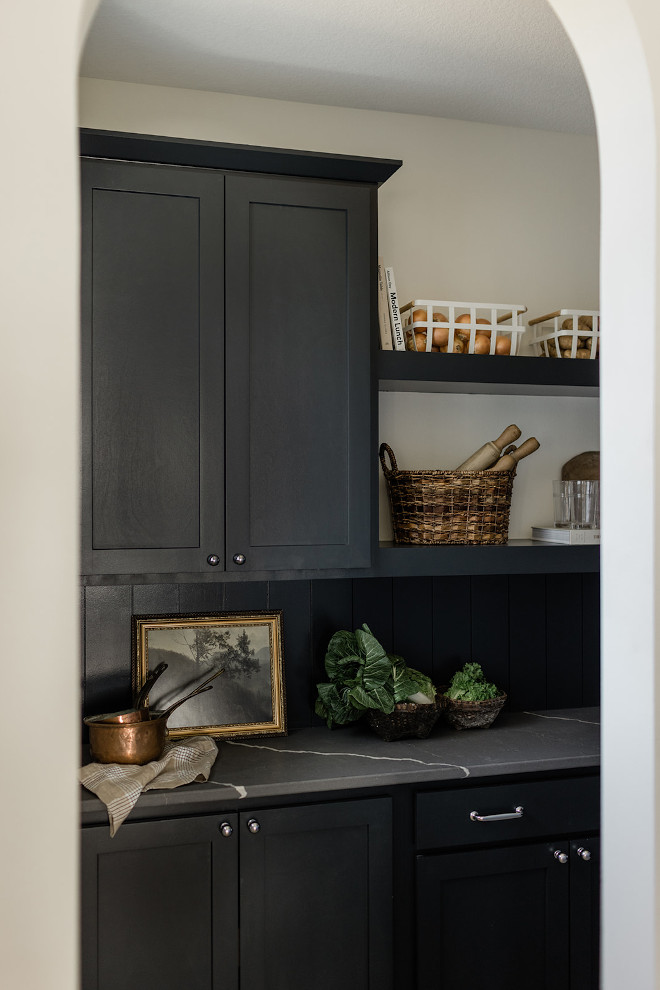 An archway leads you to a moody walk-in pantry with black cabinets soapstone quartz countertop and brick porcelain tile An archway leads you to a moody walk-in pantry with black cabinets soapstone quartz countertop and brick porcelain tile #archway #moody #walkinpantry #pantry #blackcabinets #soapstone #quartz #countertop #brick #porcelaintile