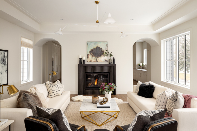 Archways open into a great room with tray ceilings and a fireplace with custom fluted concrete surround and hearth #Archways #greatroom #trayceiling #fireplace #flutedconcrete #fireplacesurround