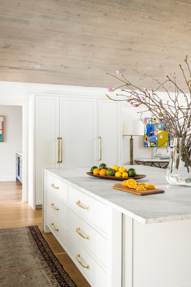 White kitchen features oversized waterfall marble kitchen island Carrara marble countertops cabinetry in Benjamin Moore Swiss Coffee Ceilings are vaulted wrapped in stained White Oak White kitchen features oversized waterfall marble kitchen island Carrara marble countertops cabinetry in Benjamin Moore Swiss Coffee Ceilings are vaulted wrapped in stained White Oak #Whitekitchen #oversizedkitchenisland #waterfallmarbleisland #kitchenisland #Carraramarble #countertop #cabinetry #BenjaminMooreSwissCoffee #Ceilings #vaultedceiling #wrappedceiling #WhiteOak