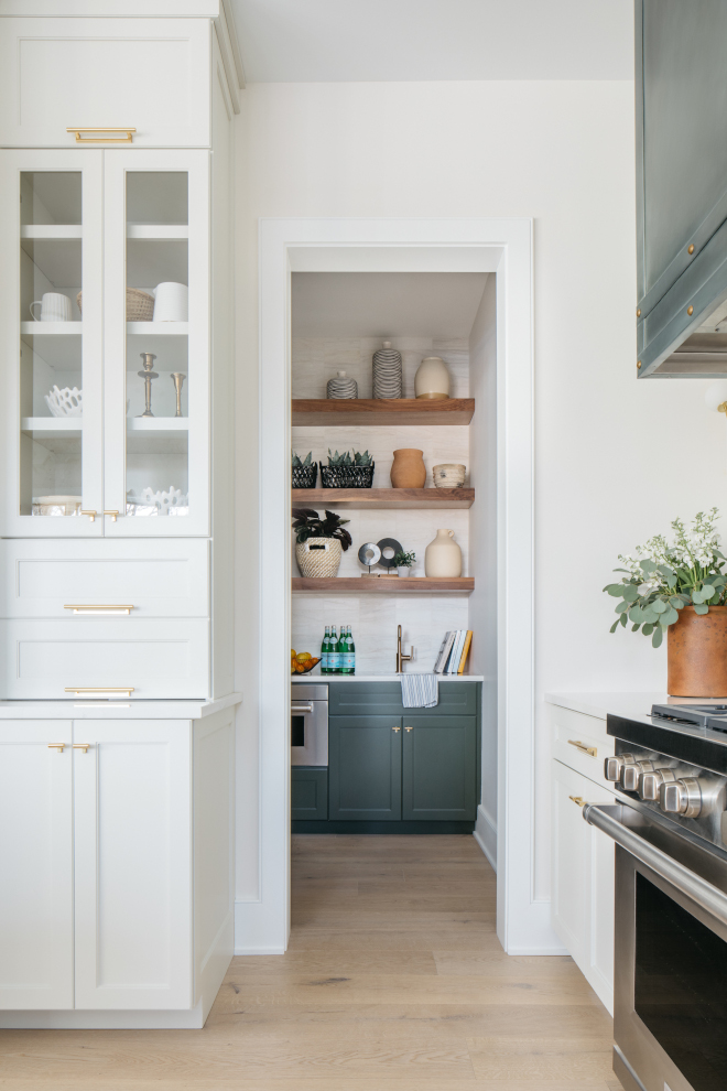 Pantry features open shelving accentuated by the same deep green hue on cabinets #pantry #pantrycabinets #pantryideas #pantrydesign