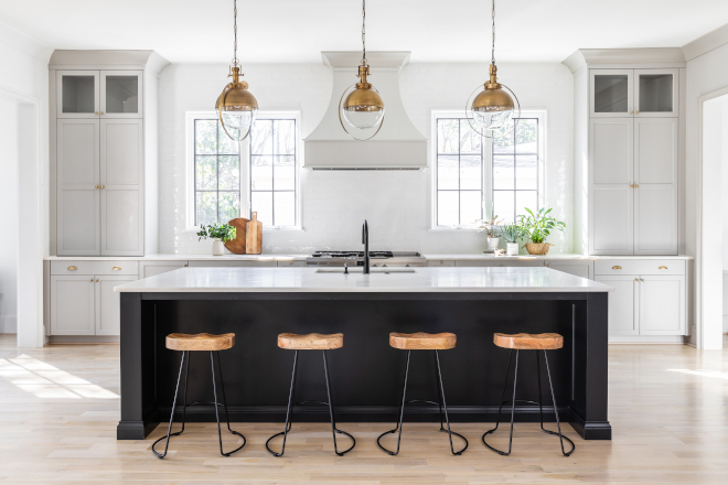 Grey kitchen perimeter grey cabinets are beautifully paired with brass hardware while a black kitchen island is accentuated with three globe pendants #Greykitchen #perimetercabinets #greycabinets #brasshardware #blackkitchenisland #globependants
