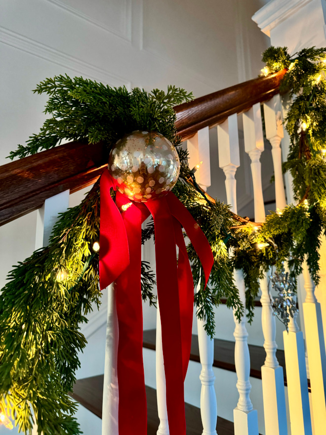 how to hang garland on stairs I secured the greenery to the railing with zip ties and I secured the ornaments and ribbon with wire #howtohanggarland #howtohanggarlandonstairs