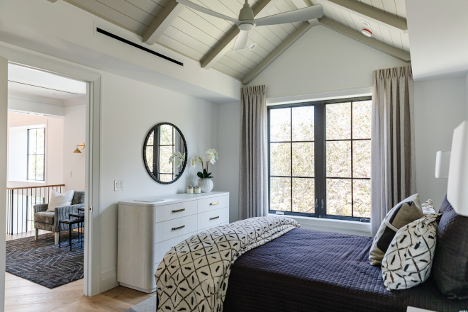 The guest bedroom features a vaulted ceiling painted in a soft grey hue and adorned with chic decor #guestbedroom #vaultedceiling #softgrey #adornedchicdecor