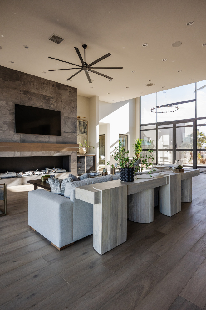 Great room The spacious foyer leads into the great room featuring a huge fireplace covered in a matte porcelain tile complemented by a white oak mantel adorned with metal detail #greatroom #fireplace #foyer