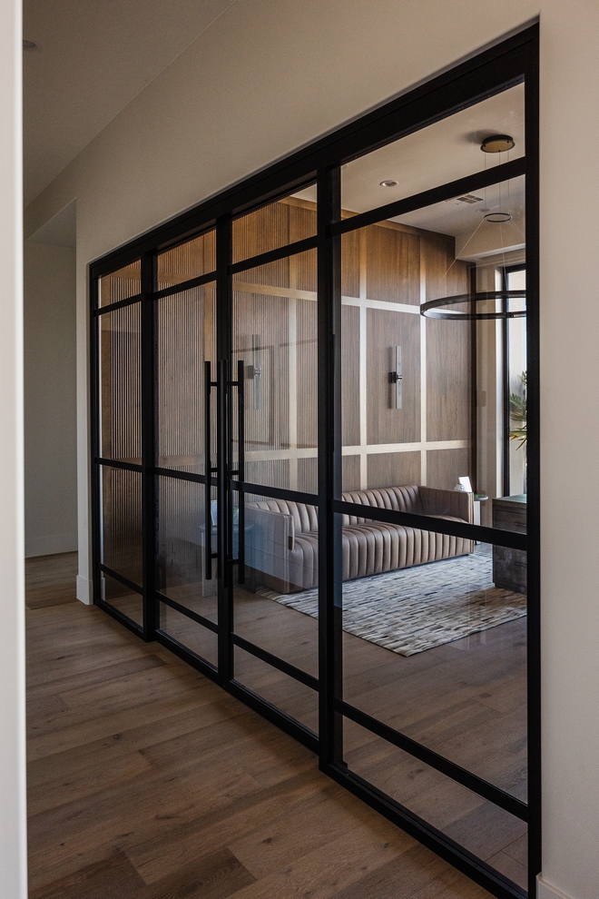The custom metal and glass sliding doors create a seamless blend of modern design and functionality The white oak reeded panels add a touch of warmth and texture inviting you to explore further into this captivating study