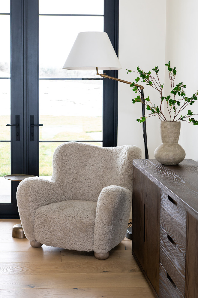 A shearling accent chair nestled in a corner beside a floor lamp forms a cozy nook to unwind #shearlingchair #accentchair #floo lamp #cozynook to unwind