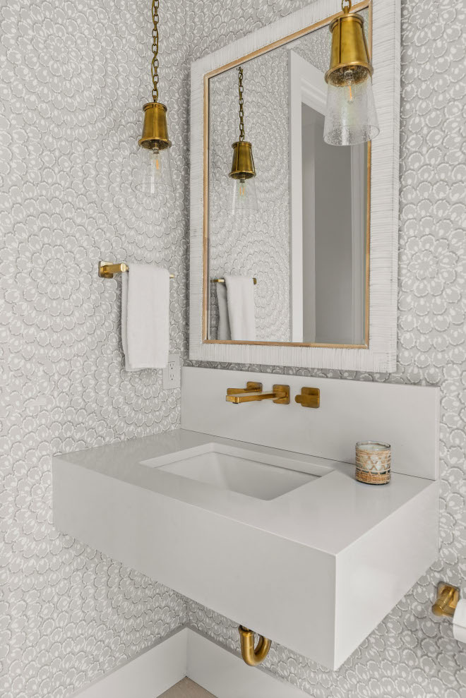 In the powder room a sleek quartz floating vanity is accentuated with a brass wall-mounted faucet while the walls feature large print wallpaper #powderroom #quartz #floatingvanity #wallmountedfaucet #largeprintwallpaper