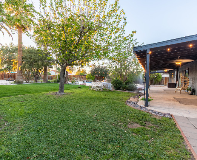 The huge fenced backyard features a pool and patios with string lights perfect for family gatherings and entertainment #backyard #stringlights