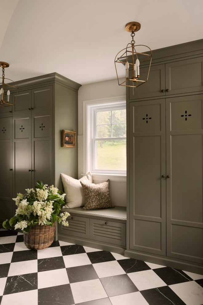 Close-up of mudroom lockers painted in Benjamin Moore Louisburg Green with brass hardware and earthy tones.