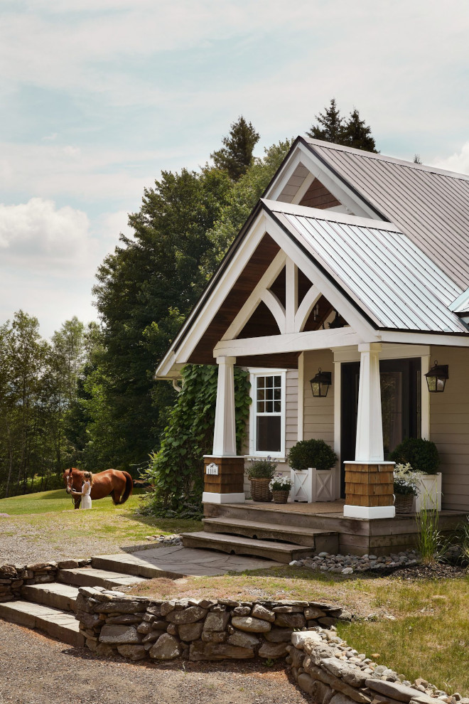 Exterior view of a French country home with shingle and hardie board siding, timber-frame gable porch, and bluestone pathway.