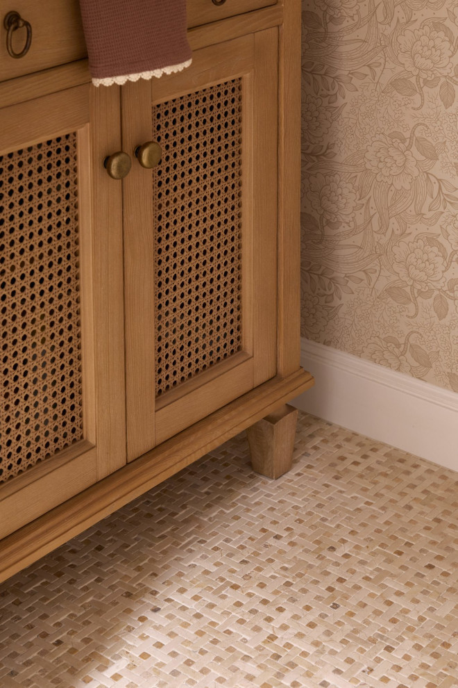 Natural Wood Powder Room Vanity with Cane Front Detail Close-up of a natural wood powder room vanity with cane cabinet doors, warm floral wallpaper, brass hardware, and a textured mosaic floor in earth tones.