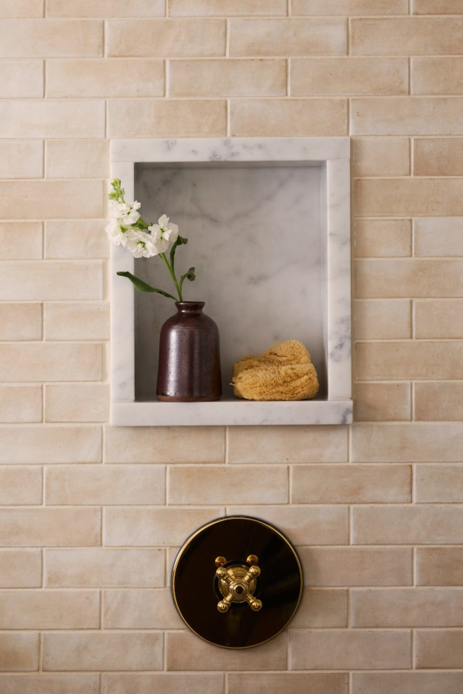 Neutral Bathroom Shower Niche with Marble Shelf and Beige Tile Earth-tone shower featuring warm beige tiles, a marble shower niche with a brown vase and sponge, and brass shower controls.