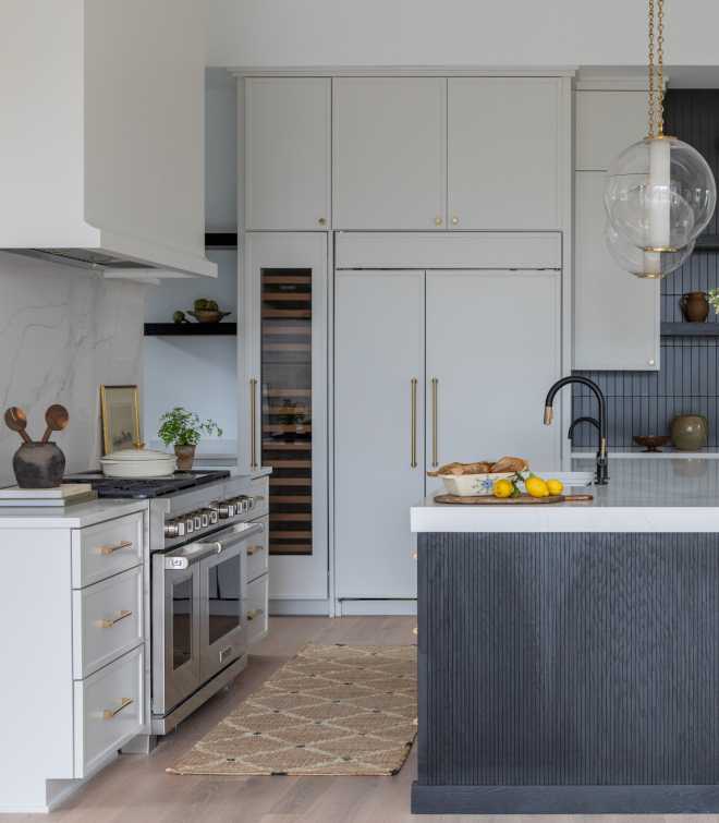 Custom drywall kitchen hood painted Sherwin Williams Heron Plume with Calacatta Izaro quartz slab backsplash. Cabinet paint color is also Sherwin Williams Heron Plume.