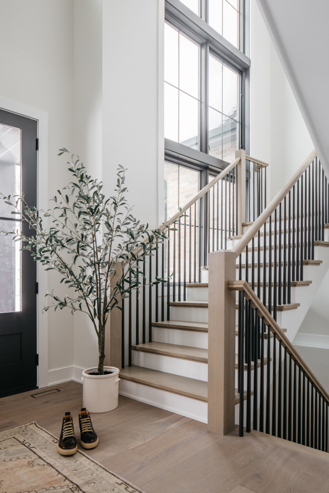 2026-new-construction-white-oak-staircase-black-balusters White oak staircase with satin black balusters and two-story windows in a new construction home