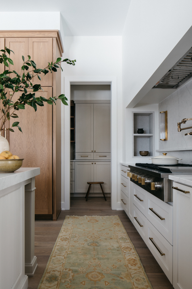 2026-new-home-cooktop-alcove-calacatta-monaco-backsplash-gossamer-veil Cooktop alcove with MSI Calacatta Monaco slab backsplash, built-in spice racks, Vanilla Milkshake walls, and Gossamer Veil cabinetry in a new construction kitchen.