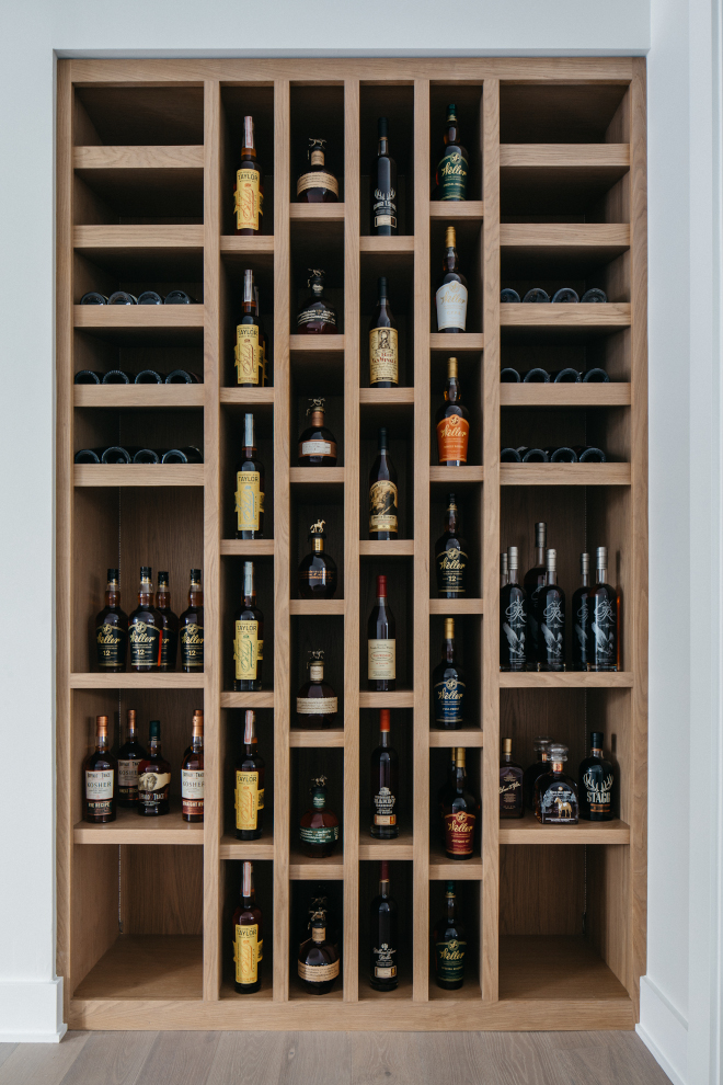 2026-new-home-foyer-white-oak-built-in-wine-rack Foyer built-in wine rack in white oak with warm gray stain, displaying wine and liquor bottles in a 2026 new construction home.