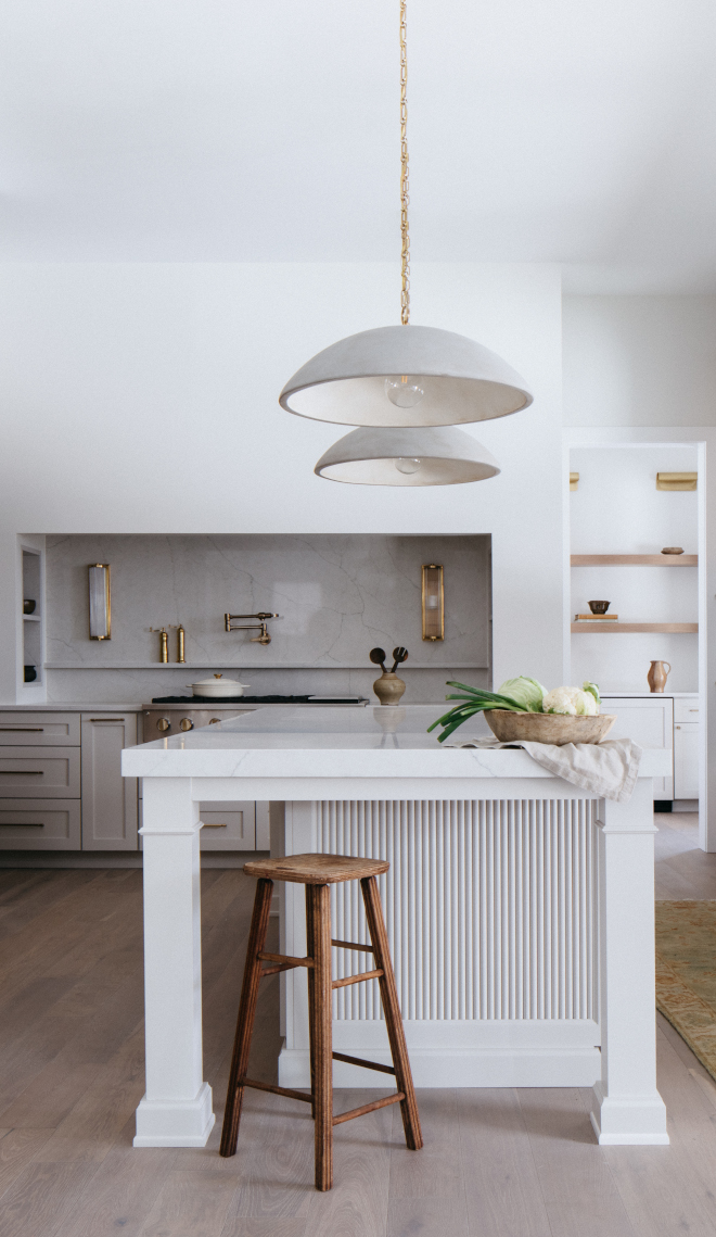 2026-new-home-kitchen-island-pendant-lighting-high-ceilings Two pendant lights centered above a long kitchen island in a high-ceiling new construction home, providing balanced task lighting and visual symmetry.