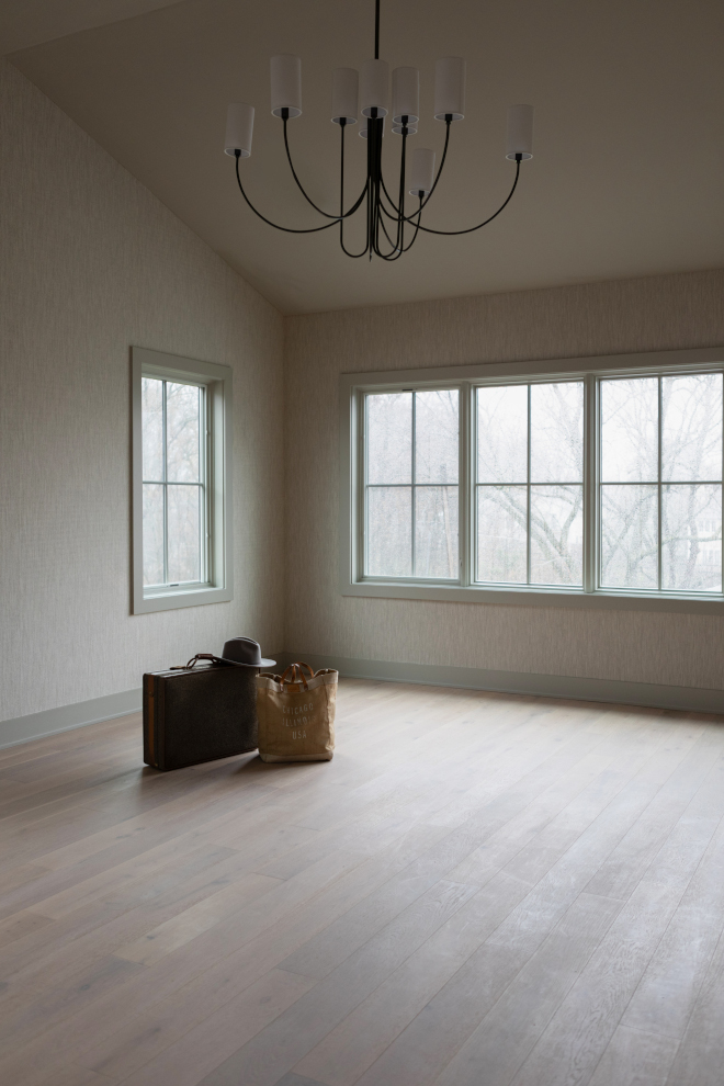 Primary bedroom with vaulted ceiling, large chandelier, wood floors, and a calm neutral color palette.
