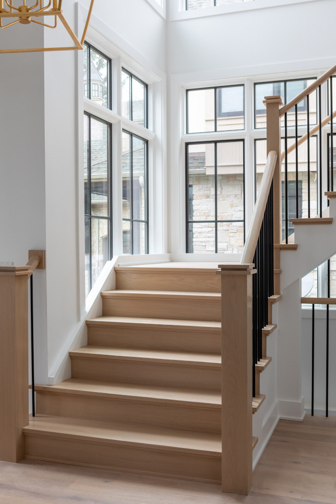 Staircase trim and window jambs painted Benjamin Moore Chantilly Lace with black windows in Sherwin Williams Iron Ore.