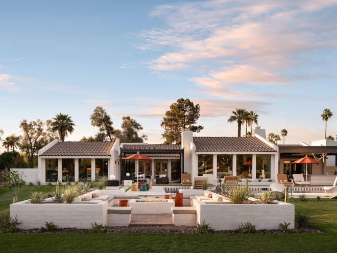 Mid-century modern backyard patio with low white architectural seating walls and large firepit, earthy tones and natural landscaping.