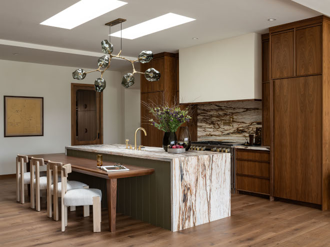 Arizona mid-century modern kitchen with massive waterfall island, built-in walnut table, twin skylights, warm neutral walnut cabinets, and sculptural chandelier.
