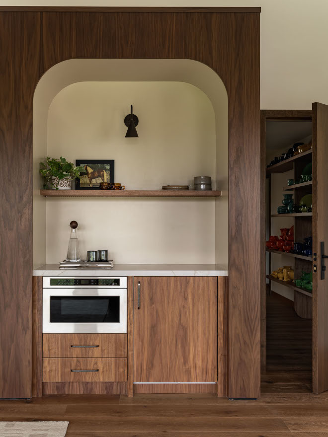 Bar tucked into arched nook in bedroom with flat slab walnut cabinetry and Pental Quartz Tramonto countertop.