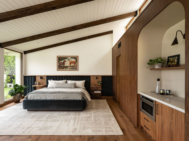 Bedroom with sloped ceiling, upholstered mid-century modern bed with channeled velvet panels, walnut nightstands, and custom walnut wall paneling with arched bar nook.