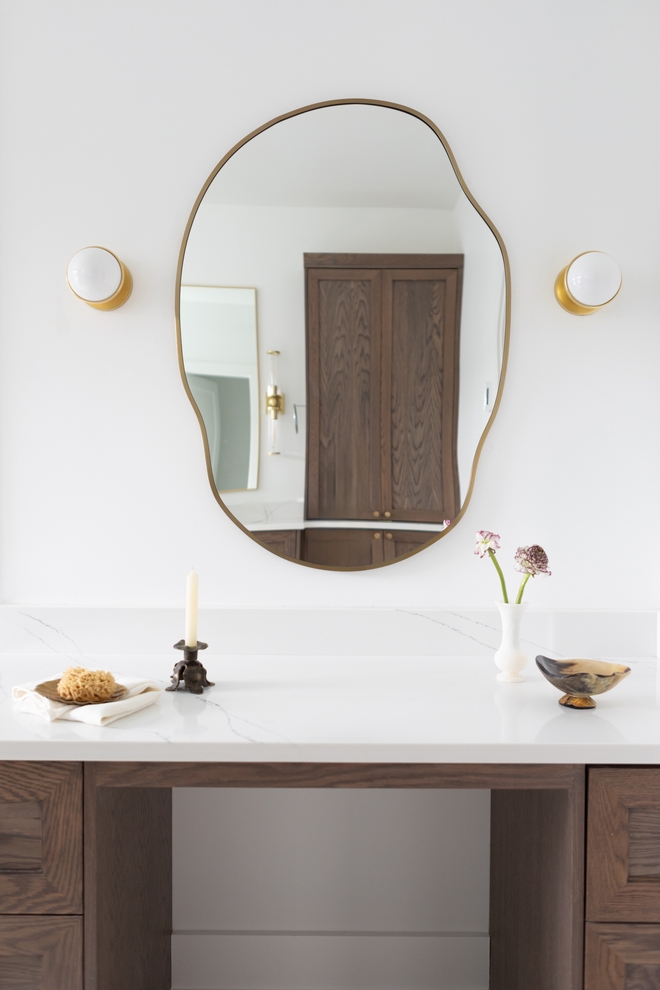 Custom makeup vanity area in primary bathroom featuring white oak cabinetry and an organic-shaped mirror.