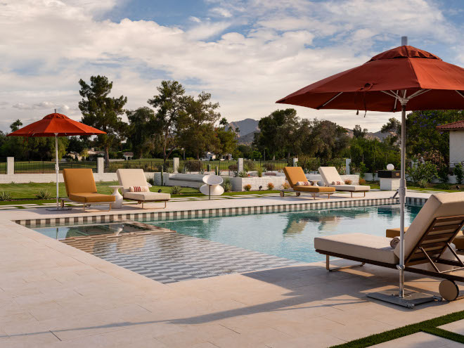 Large pool with surrounding lounge chairs in mid-century modern backyard, promoting joyful and relaxing outdoor living.