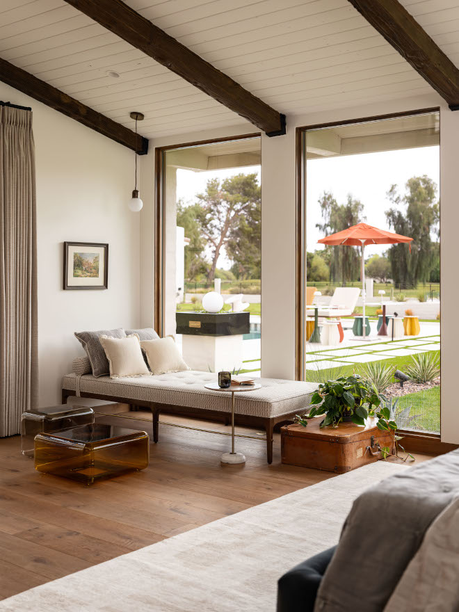 Bedroom daybed with view of backyard, natural light highlighting warm mid-century modern interior palette.