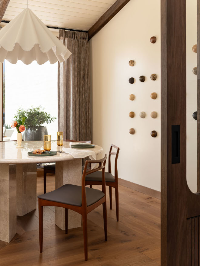 Vintage Johannes Andersen teak dining chairs in mid-century modern dining room, with dome ceramic wall art on walls.