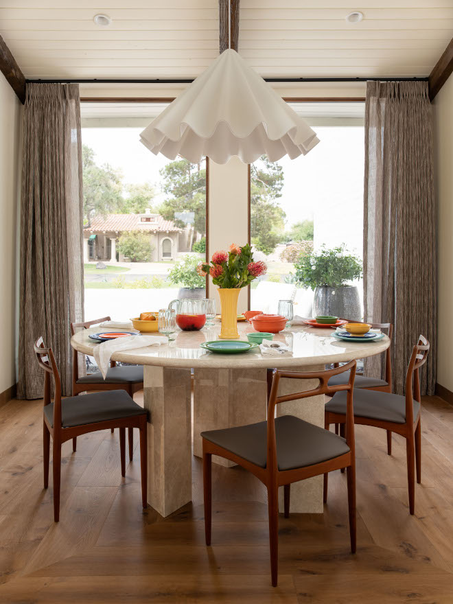 Mid-century modern dining room with large windows, picture-frame wood floor pattern, round dining table, and 1960s vintage teak dining chairs.