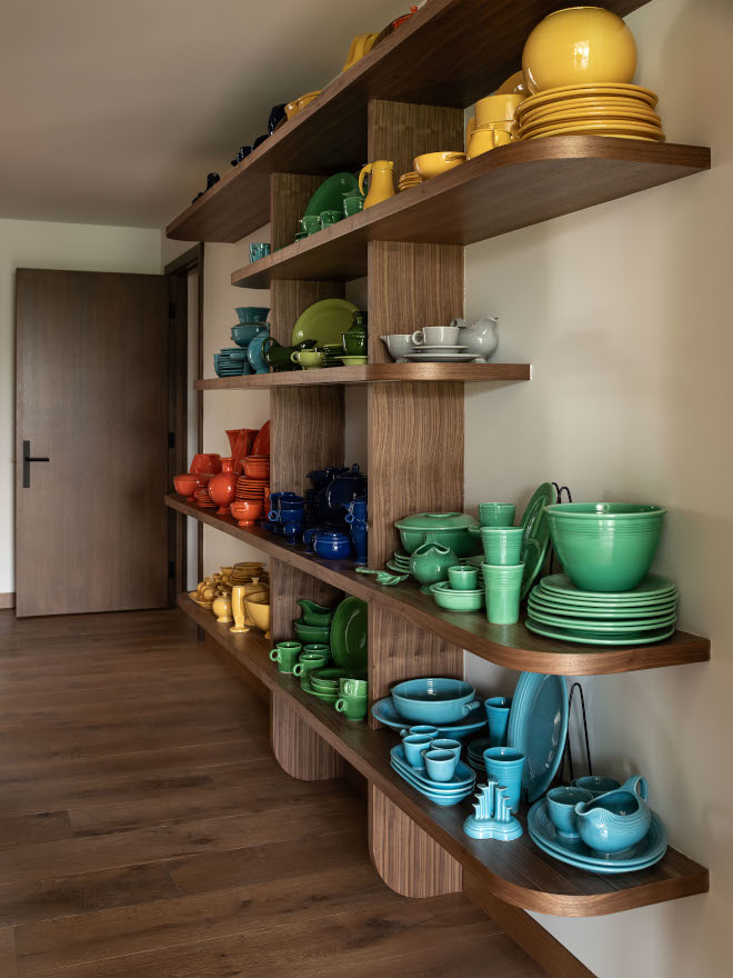 Custom open shelves in hallway with vertical supports, painted in SW 9109 Natural Linen, showcasing colorful dinnerware in mid-century modern style.