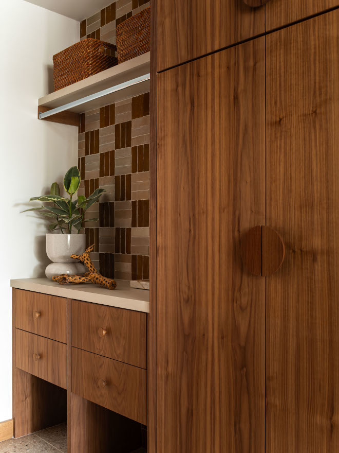 Walnut laundry cabinets with folding area, open storage for baskets, and rod above counter, backsplash with zellige crosshatch tile.