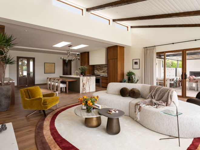 Curved two-sided sofa in mid-century modern living room, warm white walls, sloped ceiling, and inviting natural light.