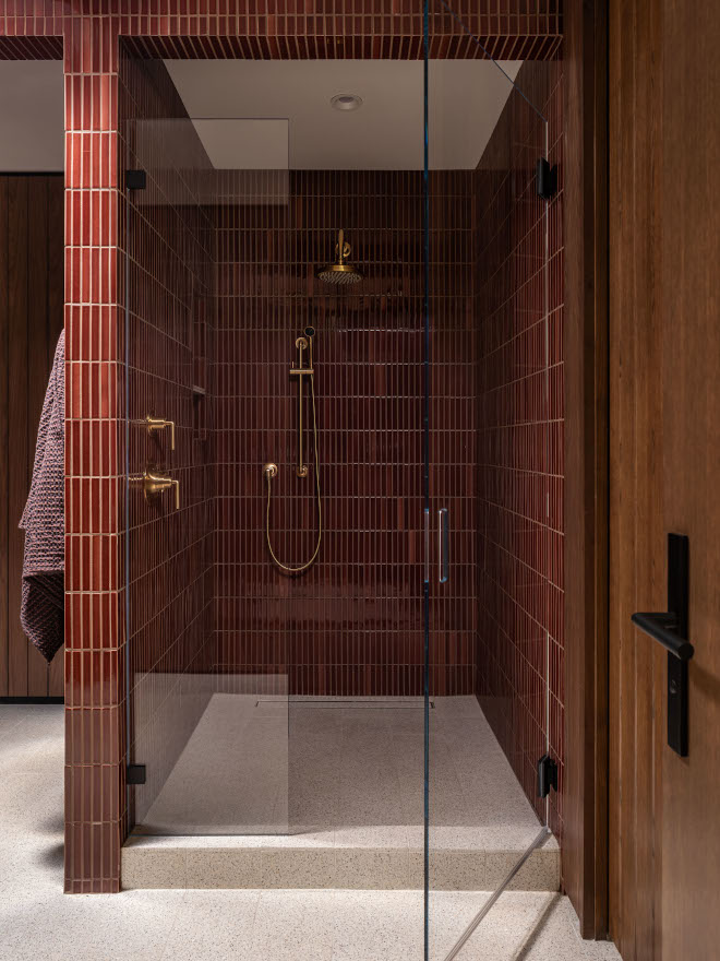 Bathroom shower featuring vertical-stacked 1"x6" Zellige pencil tiles in warm tones and matte honed terrazzo floor, creating a textured, mid-century modern inspired look.