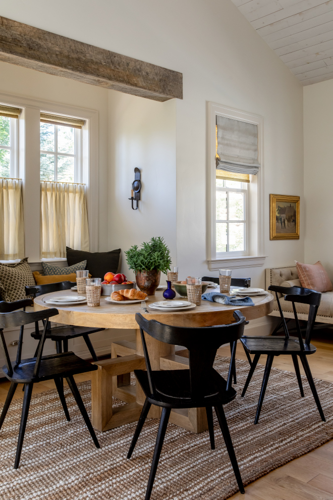 Cozy breakfast room with vaulted pine shiplap ceiling, Benjamin Moore Bone walls, custom banquette, and striped café curtains in a French Country mountain home