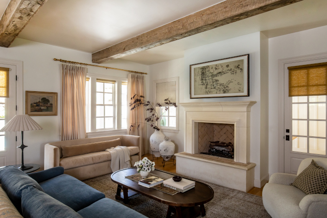 Family room with curved velvet sofa, Swiss Coffee painted walls, and linen draperies with brass hardware in a French Country mountain home