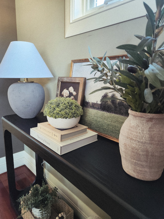 Console-table-home-decor-ideas Entryway console table styled with neutral table lamp, artwork, books, baskets, and natural décor.