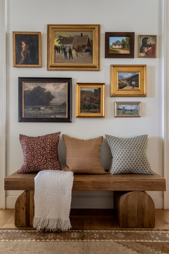 Entry hall with chunky wood bench, layered pillows, and gallery wall of vintage-style framed artwork in a mountain home