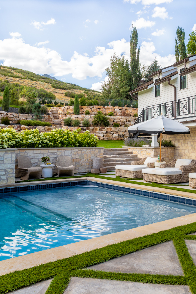 Mountain home backyard with pool, diamond-pattern concrete pavers, grass in between, hydrangea-filled garden beds, and hillside retaining walls, perfect for outdoor relaxation