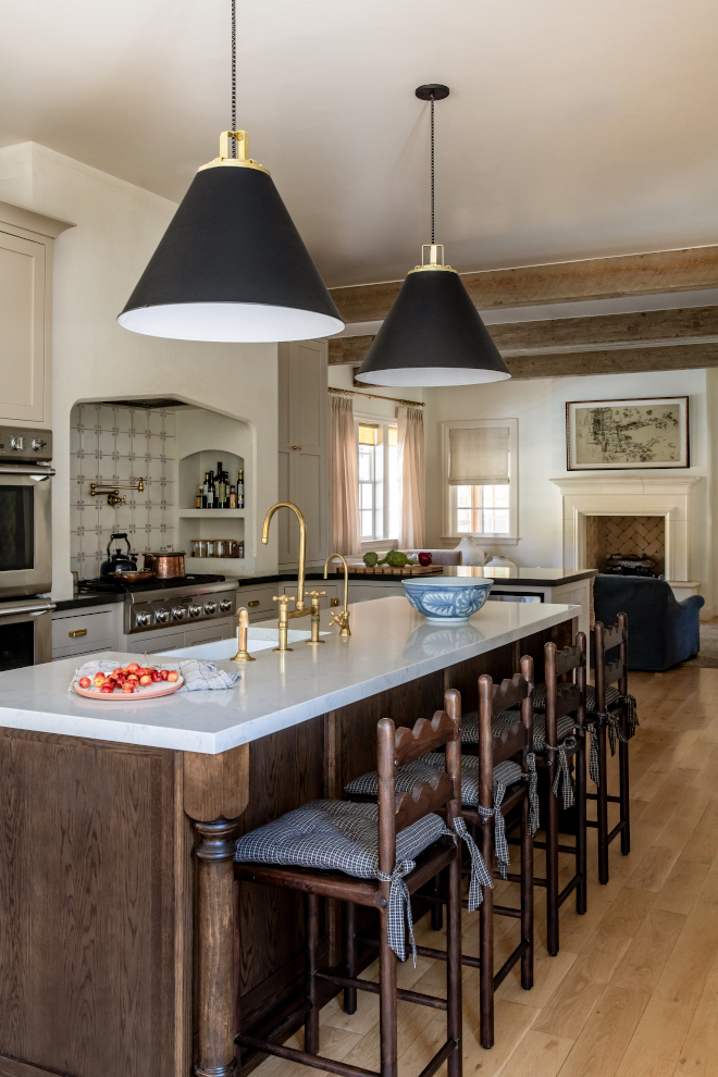 French Country mountain kitchen featuring light taupe cabinets, plastered arch range hood, hand-painted Portuguese tile backsplash, marble-look quartz countertops, and rustic wood accents for a warm, layered look